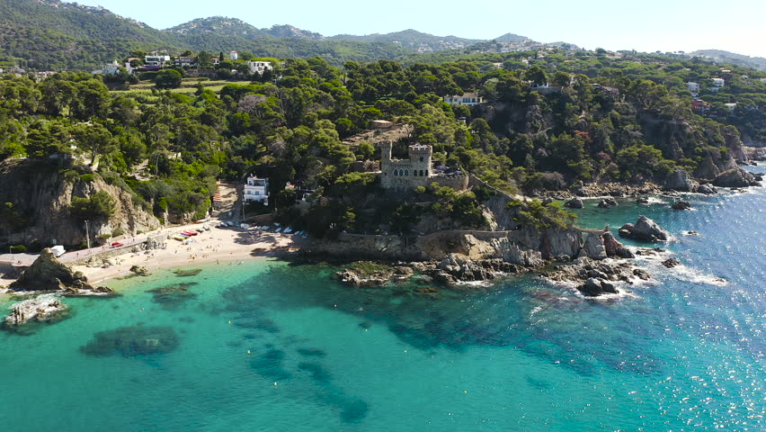 Aerial view of Lloret de Mar Castell, the iconic landmark overlooking Lloret de Mar, standing above dramatic cliffs and the blue Mediterranean Sea on the Costa Brava. 