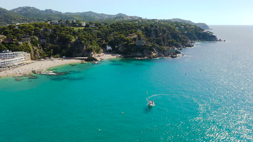 Aerial view of Lloret de Mar Castell, the iconic landmark overlooking Lloret de Mar, standing above dramatic cliffs and the blue Mediterranean Sea on the Costa Brava. 