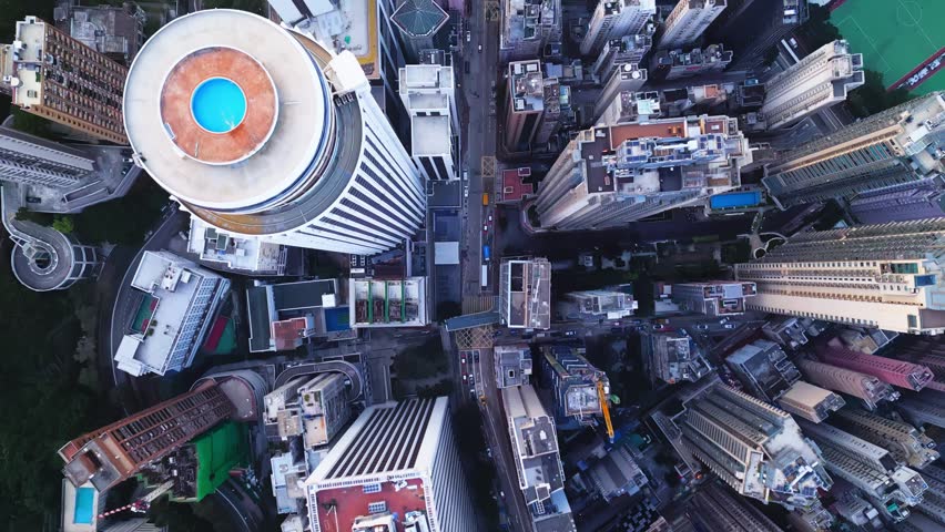 Aerial view highlights organized grid with circular roofs and narrow pathways enhancing urban design. Overhead view of Hong Kong city with streets and residential blocks creating geometric texture