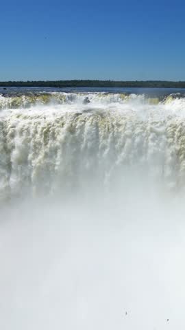 Majestic view of the iguazu falls on the border of argentina and brazil. Powerful cascades creating a dense mist with a clear sky above