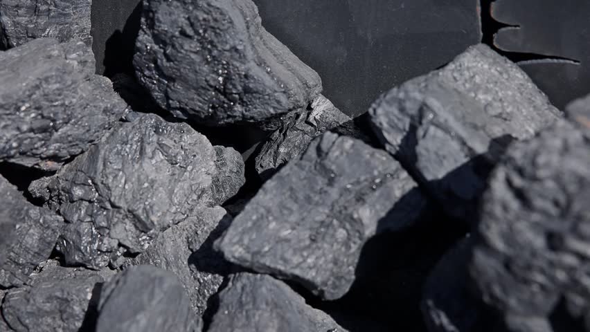 Slow motion close up of coal chunks in industrial stockpile at daytime with subtle panning tracking movement.