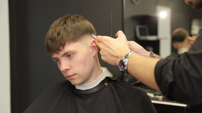 Professional barber giving a stylish haircut to a young man