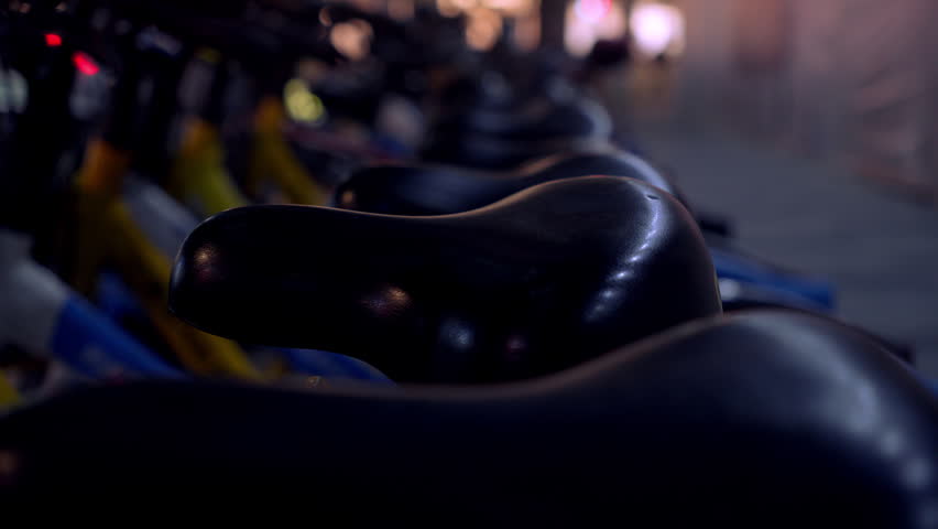 Bicycles parked at a public station during the evening hours in a city setting