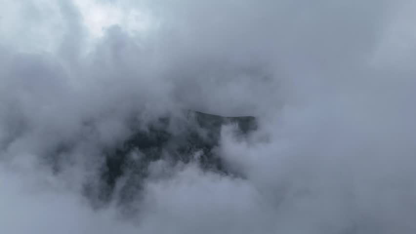 Majestic Mountain Peak Embraced by Ethereal Rolling Clouds and Dense Fog