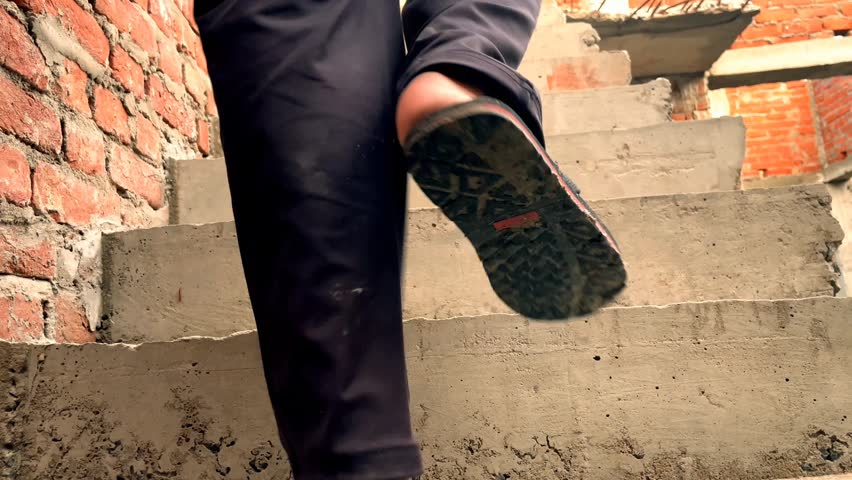 Low angle close-up of person walking upstairs in unfinished brick building