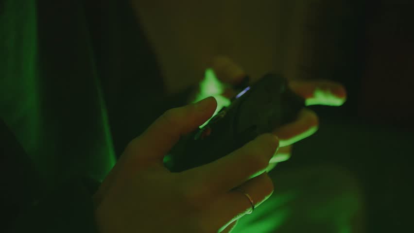 Hands Playing a Video Game on a Console in an RGB-Lit Bedroom