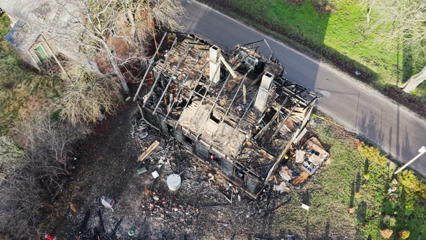 High aerial perspective shows collapsed roof and fire wrecked homestead
