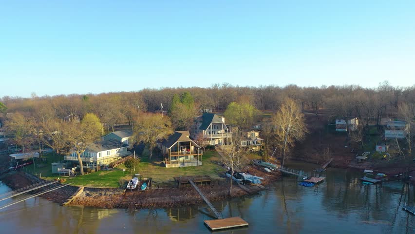 Aerial view of Table Rock Lake in Missouri, showing lakefront houses, private boat slips, still water, tree-lined banks, and peaceful shoreline living near a quiet cove.