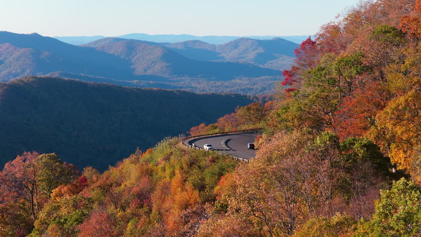 Autumn landscape in Appalachian Mountains of Tennessee featuring parked car at roadside overlook with panoramic forest views.