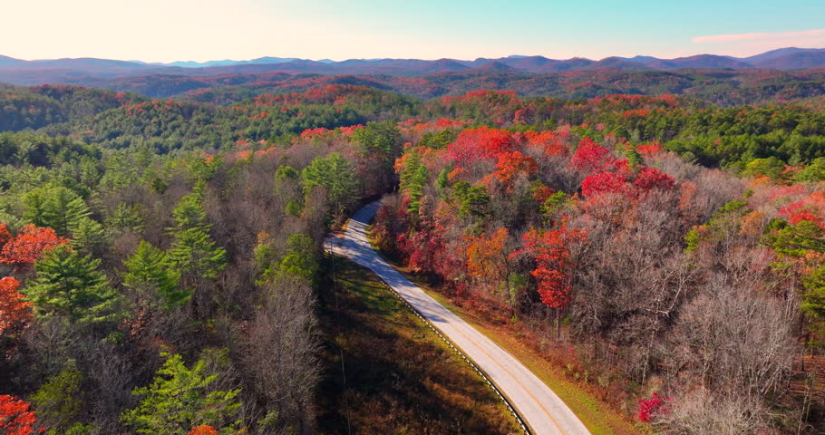 Blue Ridge Parkway at sunset in autumn. Scenic route between majestic mountain hills covered in golden and scarlet leaves.