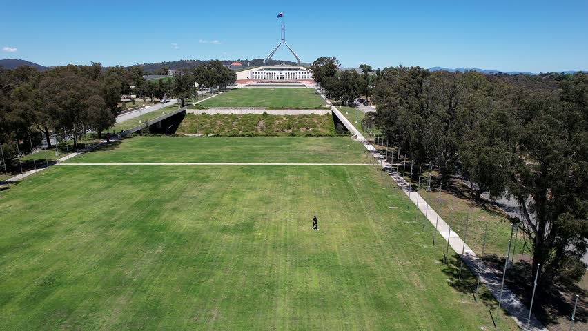 Aerial view of Parliament House with expansive green lawns and surrounding trees in Canberra, Australian Capital Territory, Australia.