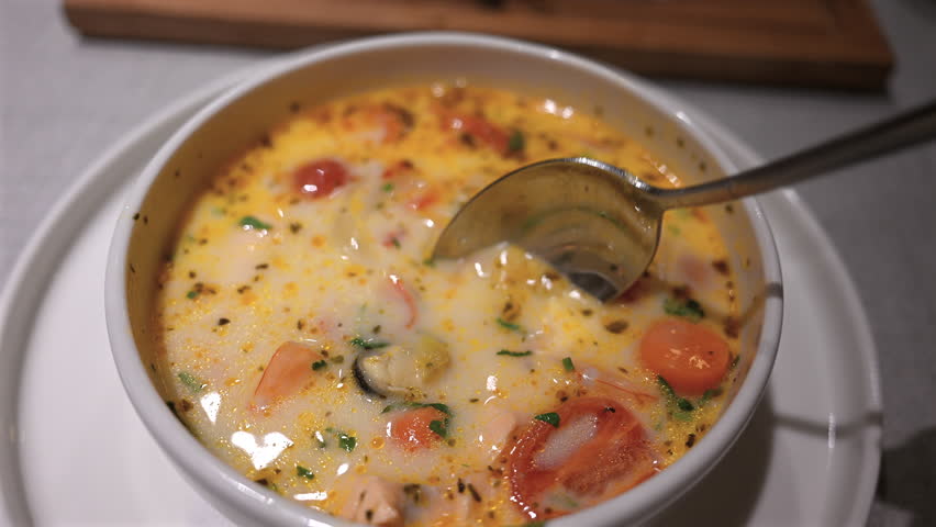 Close up of a spoon lifting shrimp from a creamy seafood soup