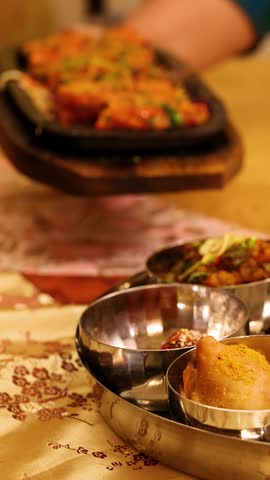 Close-up panning shot of a diverse Indian meal platter on a restaurant table.