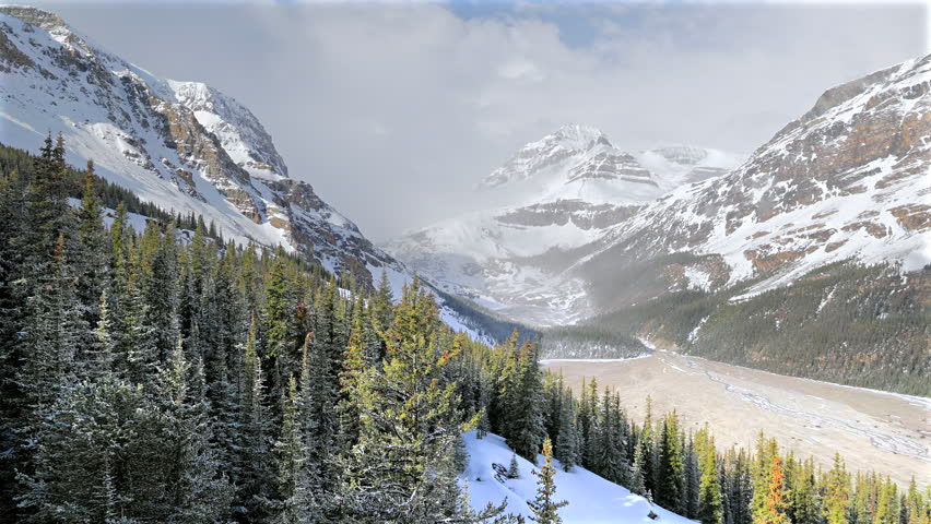 Dramatic video of frozen Peyto Lake and the glacier valley beneath snow covered mountain peaks in Banff National Park Alberta Canada.
