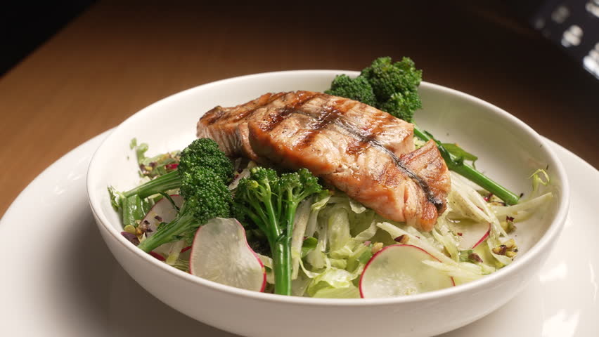Delicious grilled salmon fillet on a fresh vegetable salad with broccoli and radish rotating, fa01