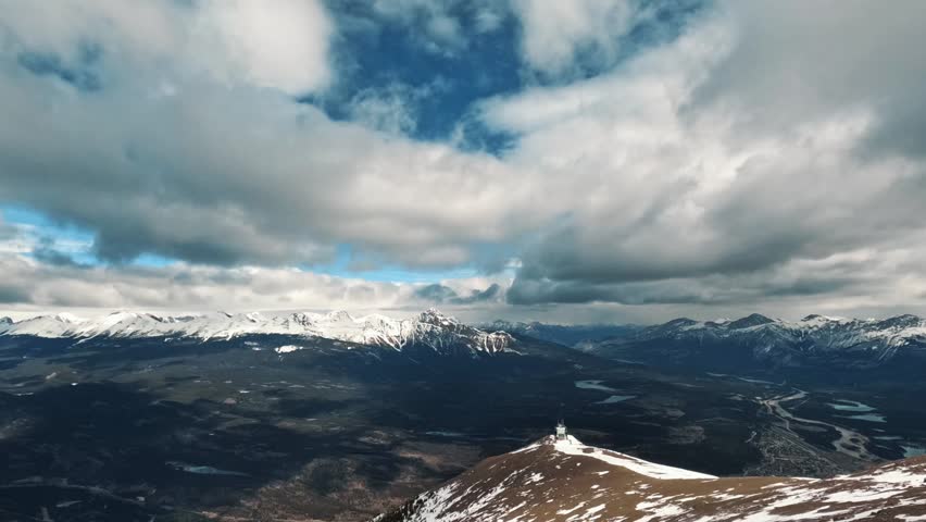 A breathtaking time-lapse of dramatic clouds move swiftly above the snow-covered peaks of the Canadian Rockies in Jasper, Alberta