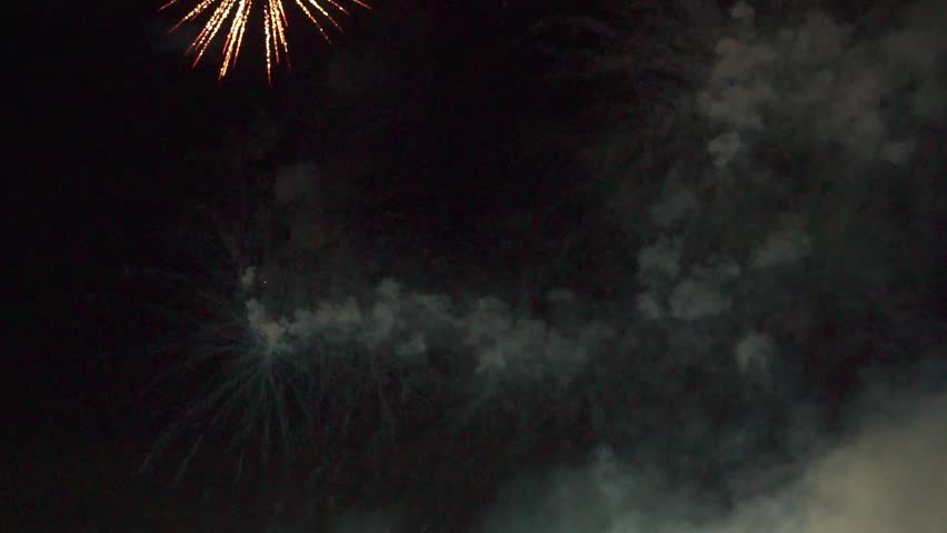 A slow motion of colorful fireworks glowing in dark sky over a racetrack at night