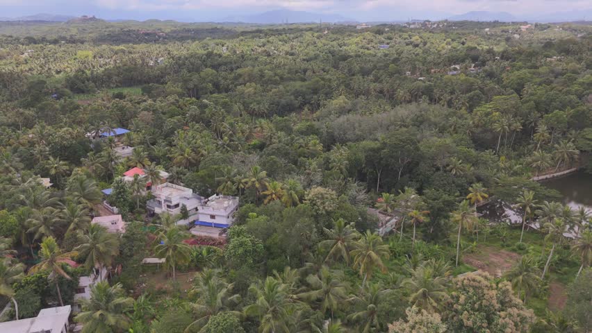 An aerial view of Cheruvarakonam Village with lush forests around the houses under cloudy sky in India
