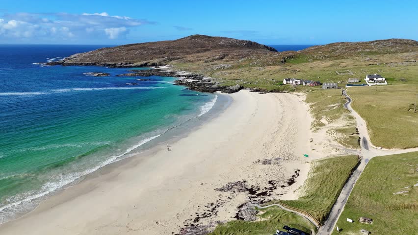 A drone view of Huisinis Beach with terrain and tranquil waters on a sunny day with blue sky in Isle of lewis and harris, Scotland