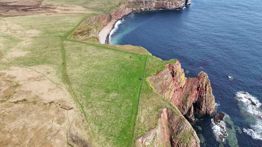 A drone fly over Duncansby Stacks overlooking blue ocean under cloudy sky in Scotland
