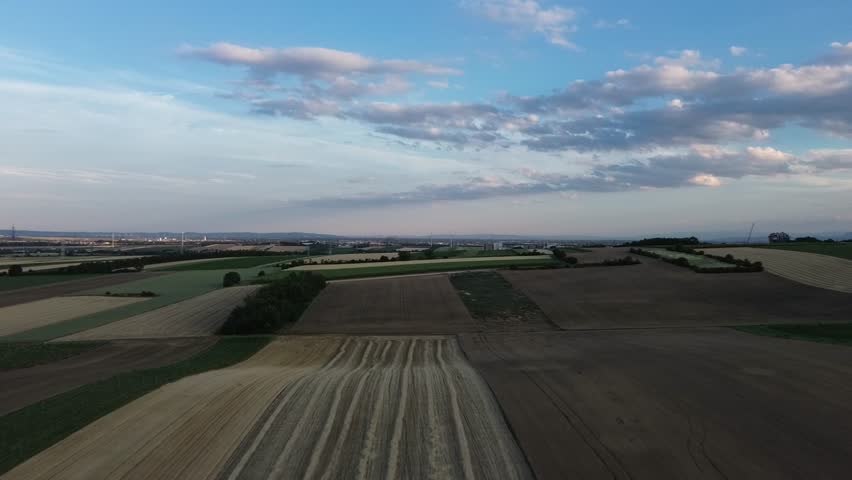 Panoramic Aerial View of Rural Agricultural Patchwork Fields and Cultivated Farmland Under a Scenic Evening Sky