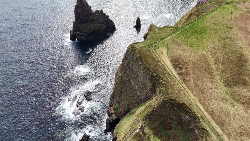 An aerial view over Duncansby Stacks with crashing waves under sunlight in Scotland
