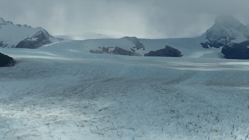 Patagonian ice field stretches across Los Glaciares National Park near El Calafate, Patagonia, Argentina, revealing fractured frozen surfaces, snow covered ridges and rugged peaks, drone lateral slide