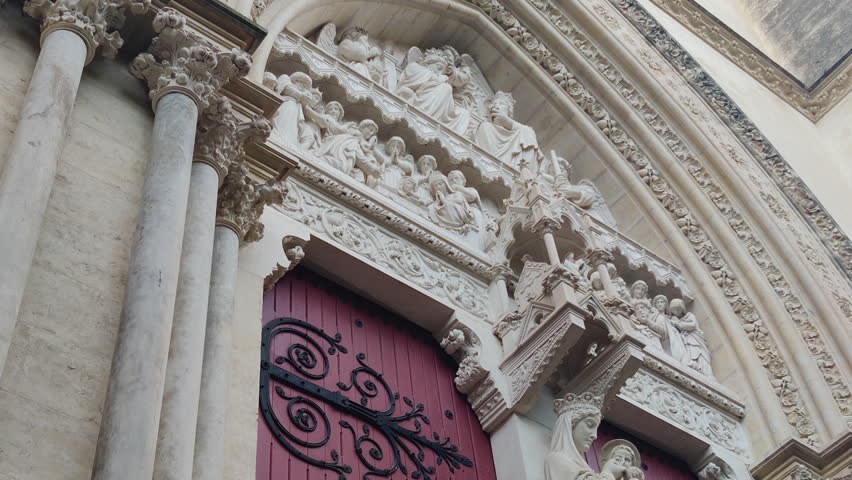 Ornate cathedral entrance with carved stone decorations and red wooden doors in Montpellier, Saint-Pierre