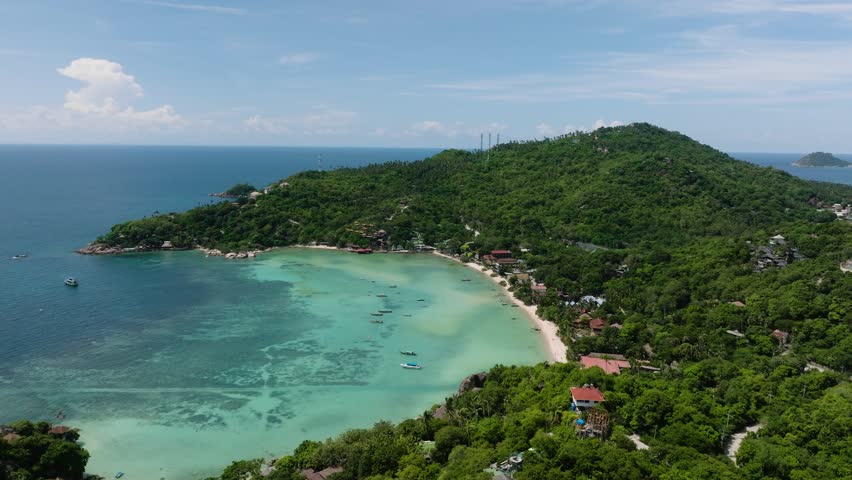 Shoreline with crystal clear water and lush tropical forest under a sunny sky. Shark Bay. Koh Tao, Thailand.
