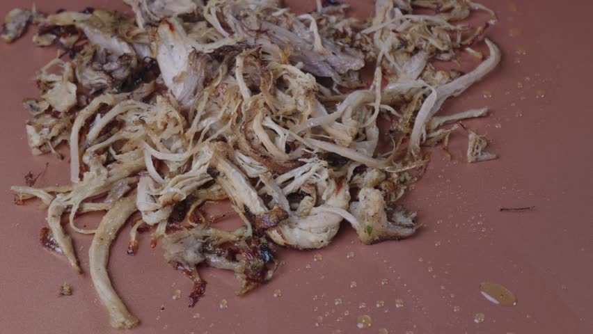 Crispy shredded carnitas pork heating on a flat griddle