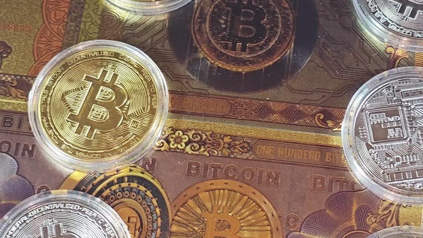 a closeup of physical bitcoins, Bitcoin (BTC), on gold plated novelty 100 bitcoin BTC notes, features Vault door open on bitcoin symbol and circuit board, cryptocurrency digital currency
