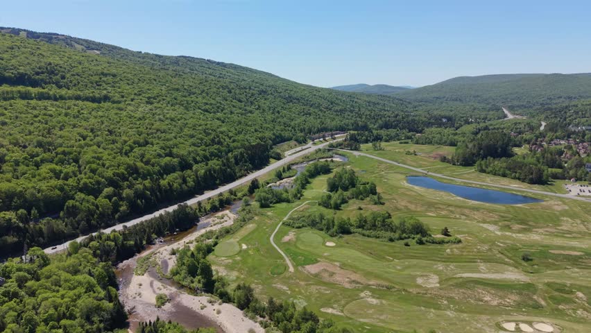 Wide aerial view from Mt Washington view toward White Mountain National Forest mountain valley landscape with winding road and small pond, New Hampshire, United States