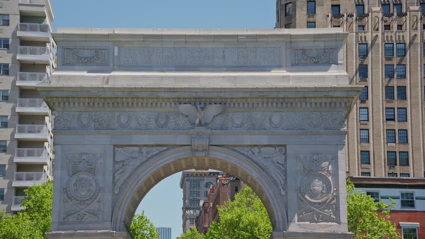 Close up of Washington Square Arch in Greenwich Village in New York City with inscription dedicated to George Washington and Fifth Avenue buildings background
