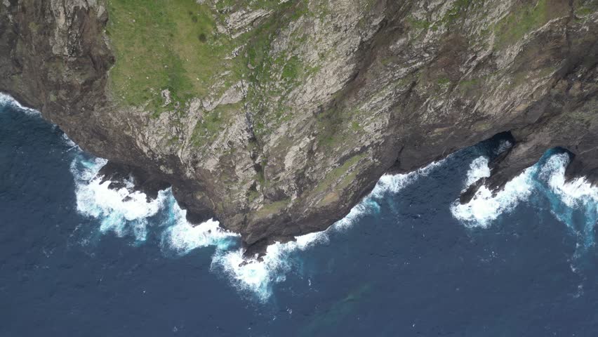 Top down aerial tracking shot along Cabo de Larano rocky coastline and crashing waves