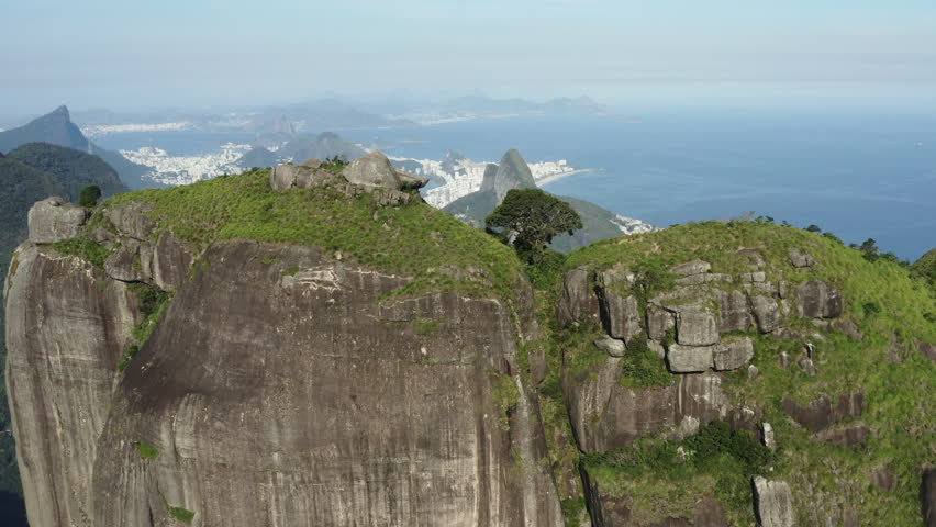 Aerial drone footage revealing Rio de Janeiro from behind Pedra da Gávea, showcasing Lagoa Rodrigo de Freitas, Morro Dois Irmãos and São Conrado Beach.