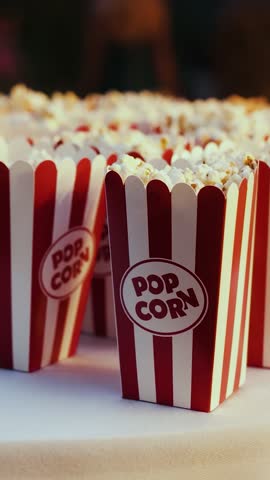 Vertical video. Red and white popcorn boxes arranged on a catering table at an outdoor wedding reception.