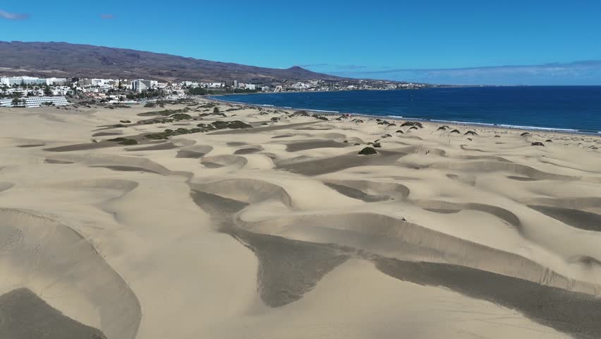 Aerial panorama flight over Maspalomas Dunes with hotels in Playa del Ingles, beach, Atlantic ocean and mountains on Canary Island Gran Canaria, Spain