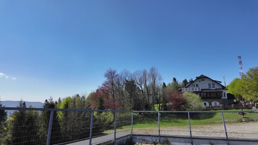 Visitors explore a bright mountain trail by a lodge, with blue sky and peaceful outdoor activity in a mountain setting.
