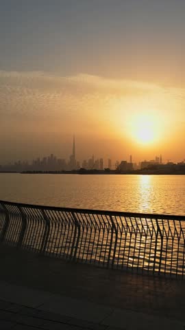 Dubai skyline, with the Burj Khalifa, view from Dubai Creek with a waterfront promenade at sunset. Luxury real estate in Dubai, UAE. Cinematic B roll of dubai. 