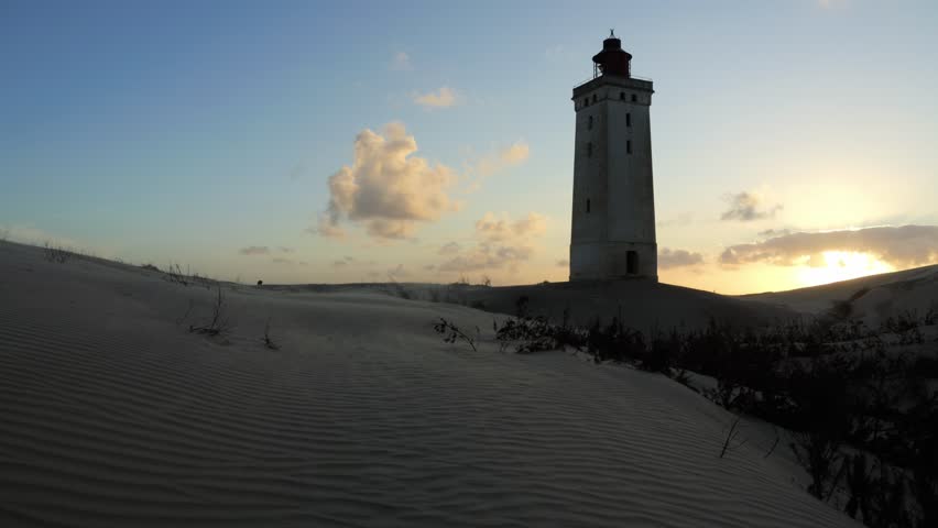 Famous Rubjerg Knude Lighthouse in Denmark on a sandy hill during a golden sunset