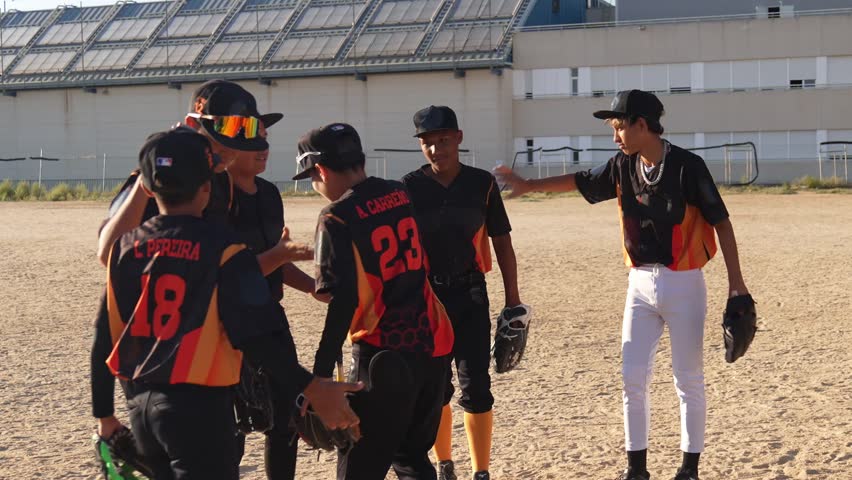 Youth baseball team celebrating a victory on the field. The teenage players high five each other, showing great teamwork and sportsmanship