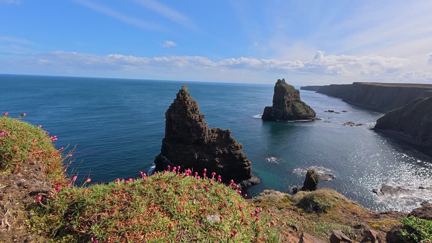 An aerial stunning shot of Duncansby Stacks with dark cliffs in blue, water in the NC500, Scotland