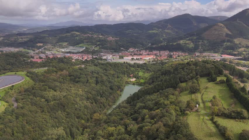 An aerial footage of the city of Bilbao in Basque Country, Spain on a sunny day with Pagasarri mountain range in the background