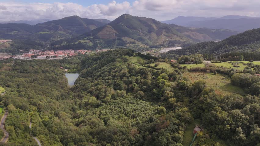 An aerial footage of the city of Bilbao in Basque Country, Spain during daytime, with Pagasarri mountain range in the background