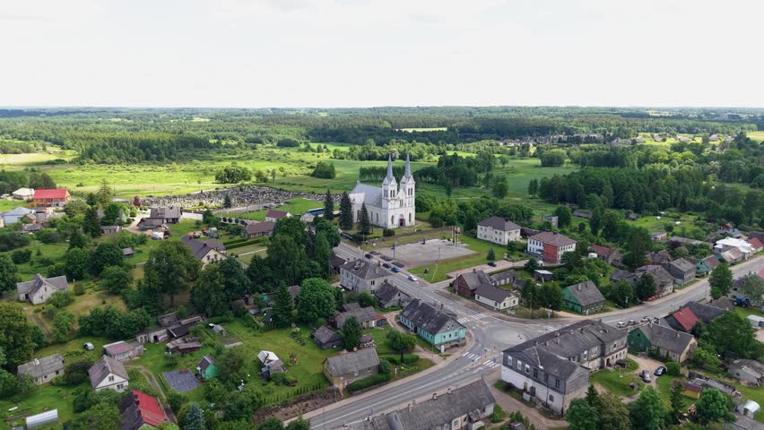 Stunning drone video captures Obeliai St. Anne’s Church, lush countryside, and quaint village houses under soft daylight, highlighting the historic landmark’s white towers and peaceful rural landscape