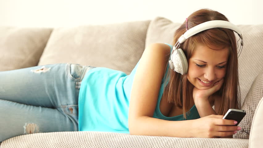 Girl listening to music and laughing at camera
