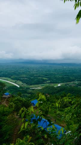 Rolling green hills covered with grass and vegetation under moving fog and clouds in tropical mountain landscape, creating a serene, dramatic countryside view of lush green hills under a partly cloudy sky, sierra, green meadow.