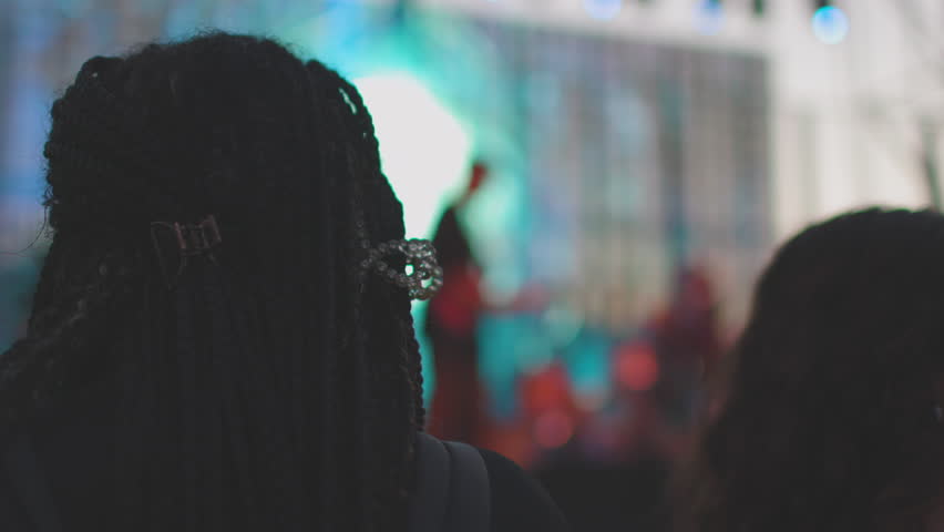 A crowd at a concert. Silhouettes of young people against bright stage lights. A rock band.