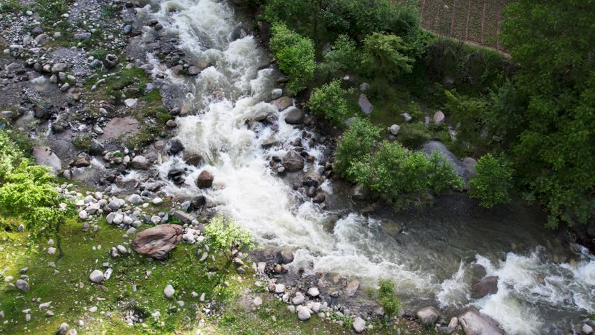 Fast-moving mountain rapids cascade over large boulders through a rocky channel in Neelum Valley, AJK