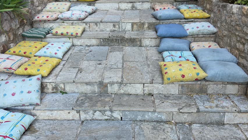 Outdoor stone staircase with colorful cushions. Cozy reading nook on stone steps.